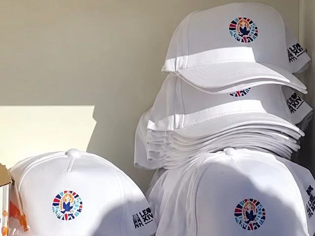 Casquettes blanches logotées aux couleurs de la visite du pape Léon XIV
