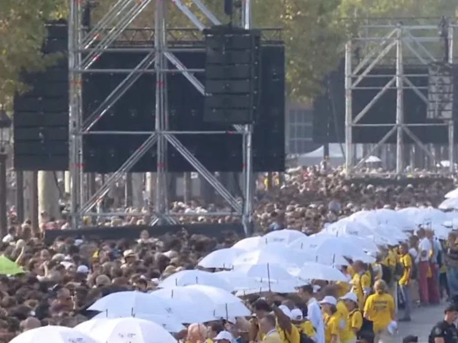 Bénévoles en jaune et haie de parapluies blancs personnalisés sur les Champs-Élysées pendant la messe du pape Léon XIV